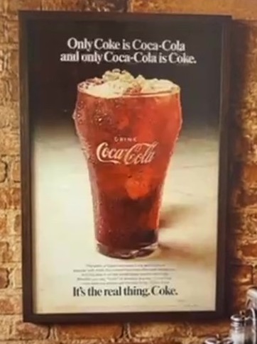 A printed Coca-Cola poster on a wall
